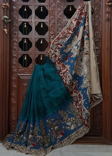 Green mul cotton kalamkari with intricate bridal procession motif and kathakali face motifs on the body of the saree.