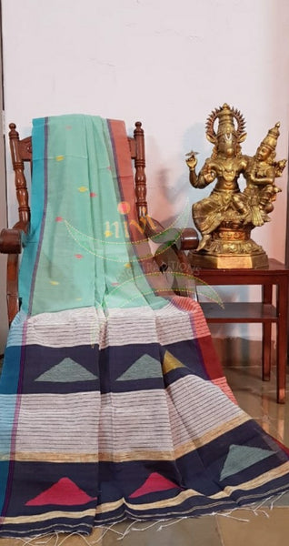 Pastel green Handloom linen with woven buttis on body, Ganga Jamuna border of orange and blue colour and woven geecha pallu.  Saree comes with contrasting navy blue blouse.