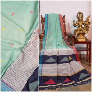 Pastel green Handloom linen with woven buttis on body, Ganga Jamuna border of orange and blue colour and woven geecha pallu.  Saree comes with contrasting navy blue blouse.