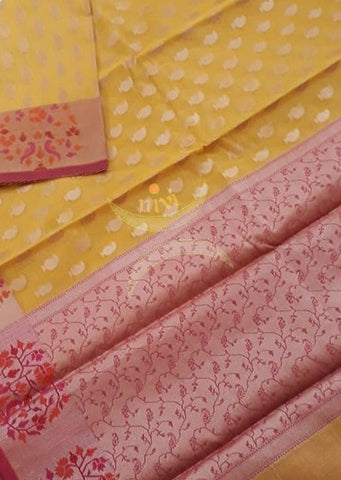 Mustard yellow silk cotton benaras brocade with contrasting pink jacquard woven border and pallu and all over antique zari butties on body. Saree comes with contrasting pink jacquard woven blouse piece matching border.