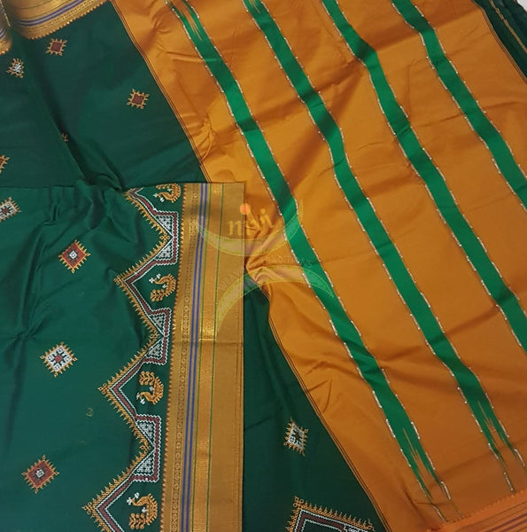 Green silk cotton ilkal with traditional peacock motif kasuti embroidery and mustard tope teni pallu. Saree comes with running blouse.