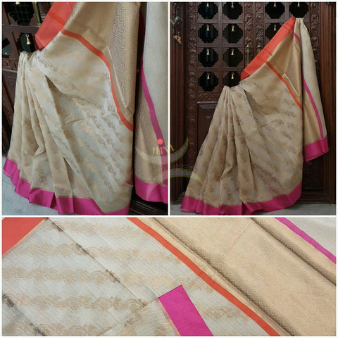 Cream shot of Gold silk cotton Benaras Brocade Supernet saree with satin finish contrasting pink orange border and antique woven antique gold zari all over the saree.
