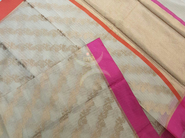 Cream shot of Gold silk cotton Benaras Brocade Supernet saree with satin finish contrasting pink orange border and antique woven antique gold zari all over the saree.