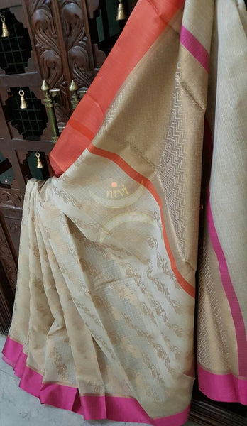 Cream shot of Gold silk cotton Benaras Brocade Supernet saree with satin finish contrasting pink orange border and antique woven antique gold zari all over the saree.