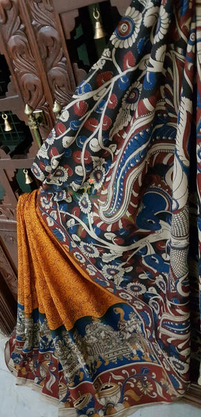 Orange mul cotton kalamkari with intricate marriage possession motif on the border and peacock motif on the pallu.