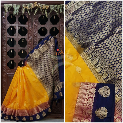 Mustard with double shaded royal blue and pink border pure south silk saree woven with floral brocade pattern on pallu and border. Saree has paisley drop booties all over.